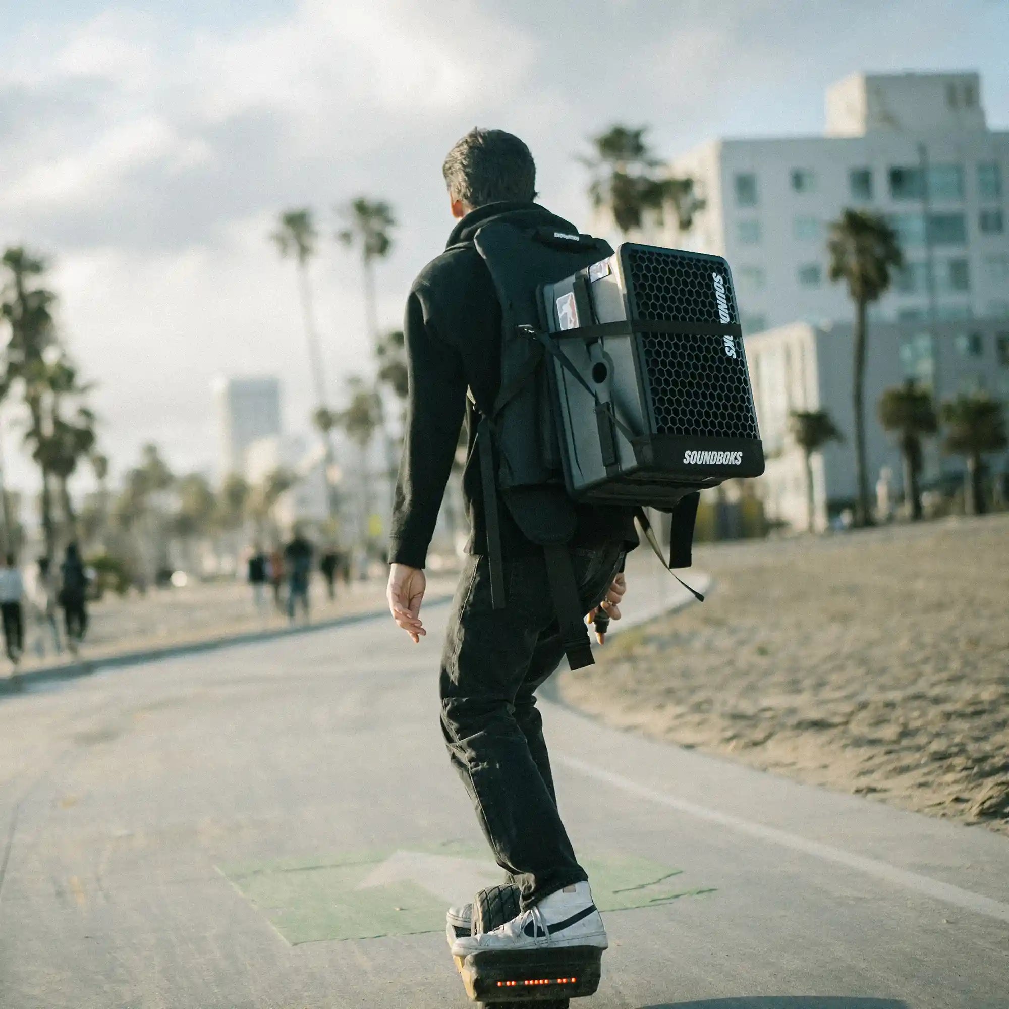 Soundboks Go strapped in Soundboks Backpack carried by a person driving on a electric skateboard