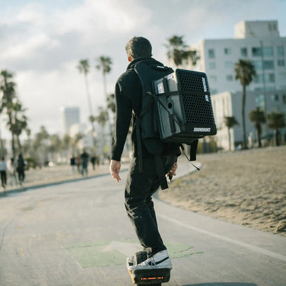 Soundboks Go strapped in Soundboks Backpack carried by a person driving on a electric skateboard